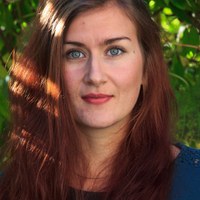 Das Bild zeigt eine lächelnde Frau mit roten langen Haaren. Dabei handelt es sich um die Projektmitarbeiterin Laura Schwiede.