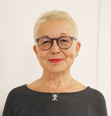 Das Foto zeigt eine lächelnde Frau mit kurzen blonden Haaren und Brille. Dabei handelt es sich um die Projektkoordinatorin Dr. Adrienne Blank-Koerber. 