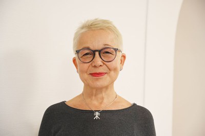 Das Foto zeigt eine lächelnde Frau mit kurzen blonden Haaren und Brille. Dabei handelt es sich um die Projektkoordinatorin Dr. Adrienne Blank-Koerber. 